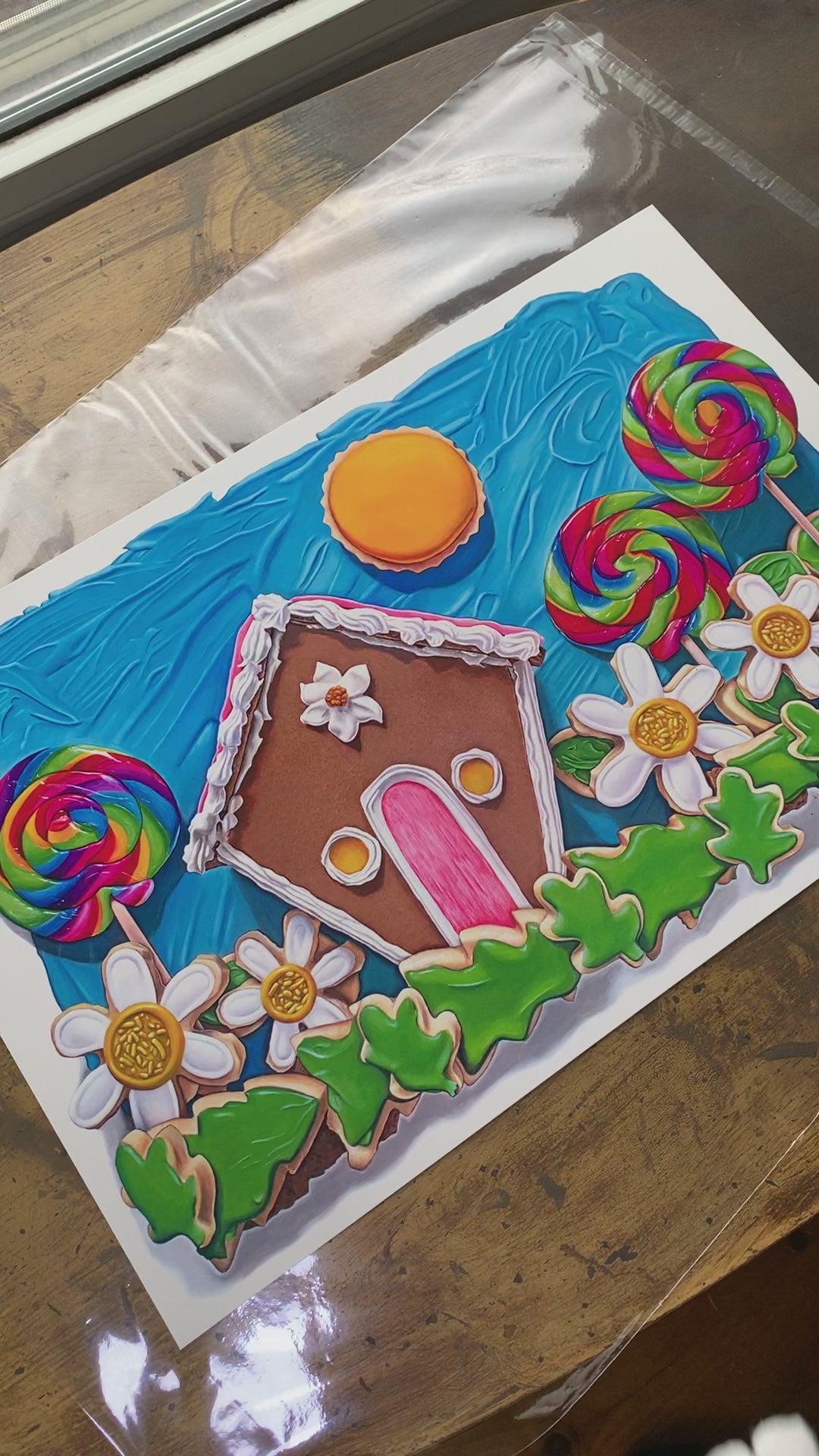 Here Comes the Sun art print by Kim Testone, based on an original ttrompe l'oeil painting of a gingerbread house among field of cookie flowers and grass, three swirly lollipops and a cookie sun, with a blue frosting sky.